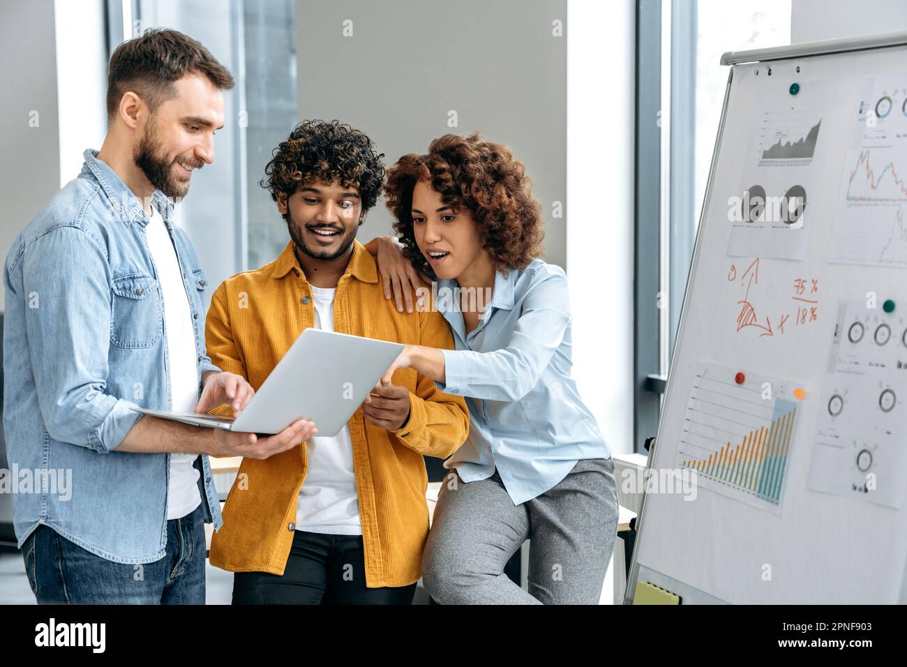 Colleghi multirazziali motivati di successo, stare vicino al cartello segnalante in ufficio, sviluppare nuove start-up, pianificare strategia, pensare alle idee, analizzare i rischi, comunicazione. Collaborazione, lavoro di squadra Foto Stock