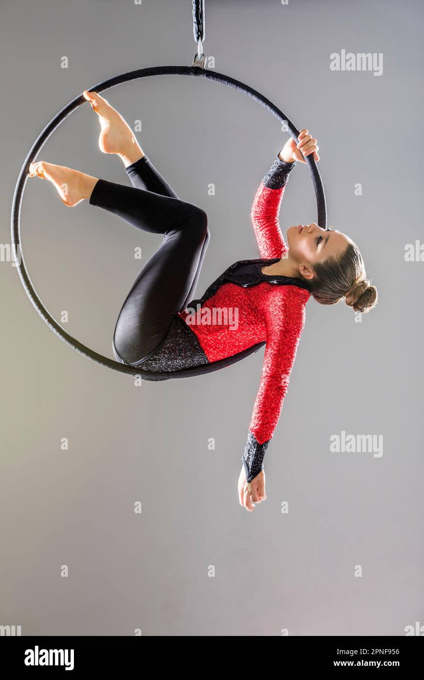 Ragazza adolescente (14-15) pratica di danza aerea sul cerchio di ginnastica Foto Stock