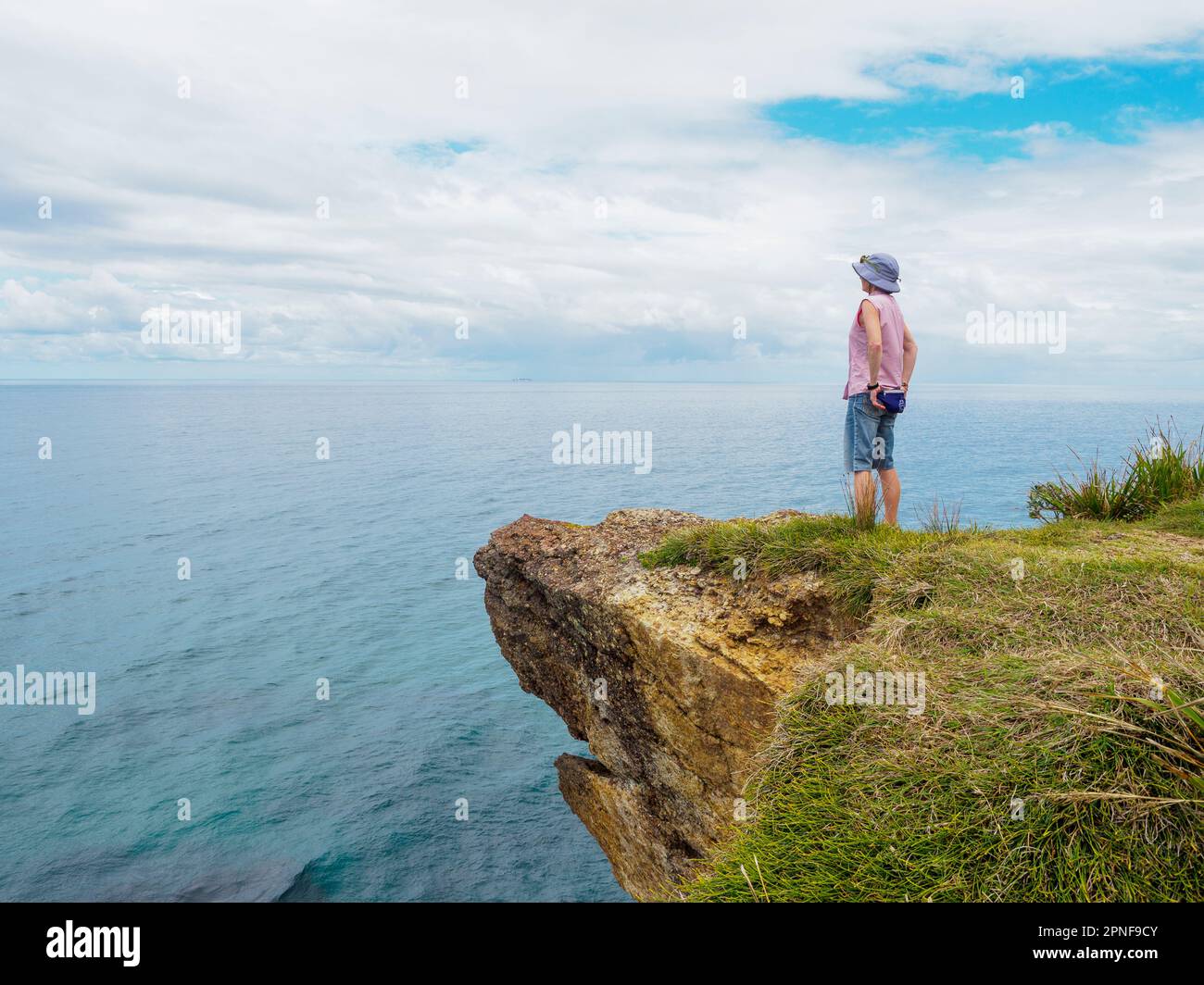 Australia, nuovo Galles del Sud, Port Macquarie, Donna in piedi sulla scogliera e guardando la vista Foto Stock