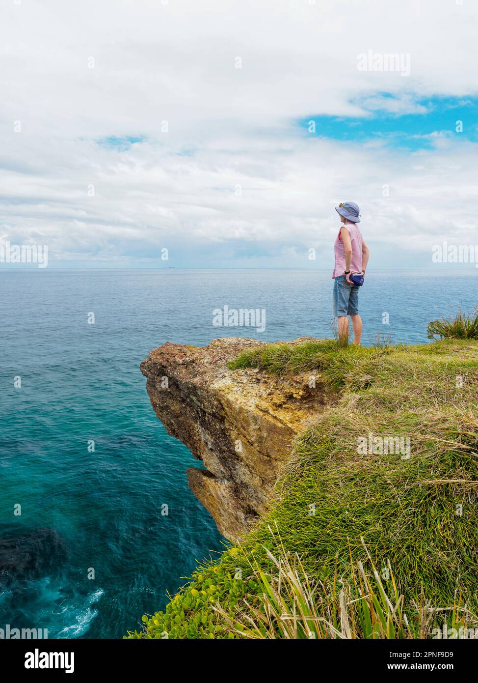 Australia, nuovo Galles del Sud, Port Macquarie, Donna in piedi sulla scogliera e guardando la vista Foto Stock