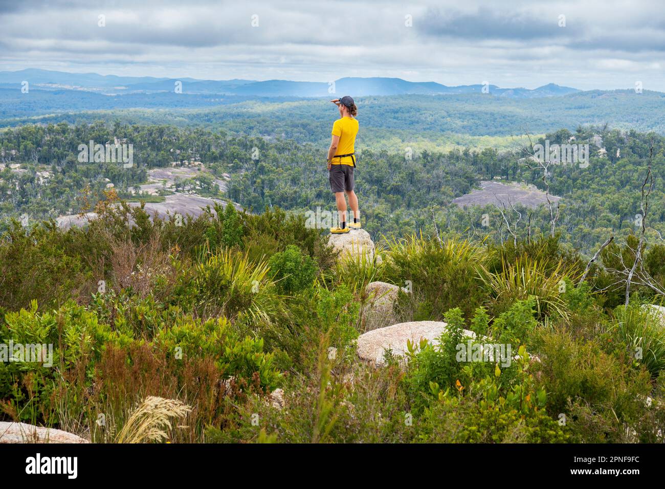 Australia, nuovo Galles del Sud, Bald Rock National Park, uomo in piedi sulla roccia e guardando intorno Foto Stock