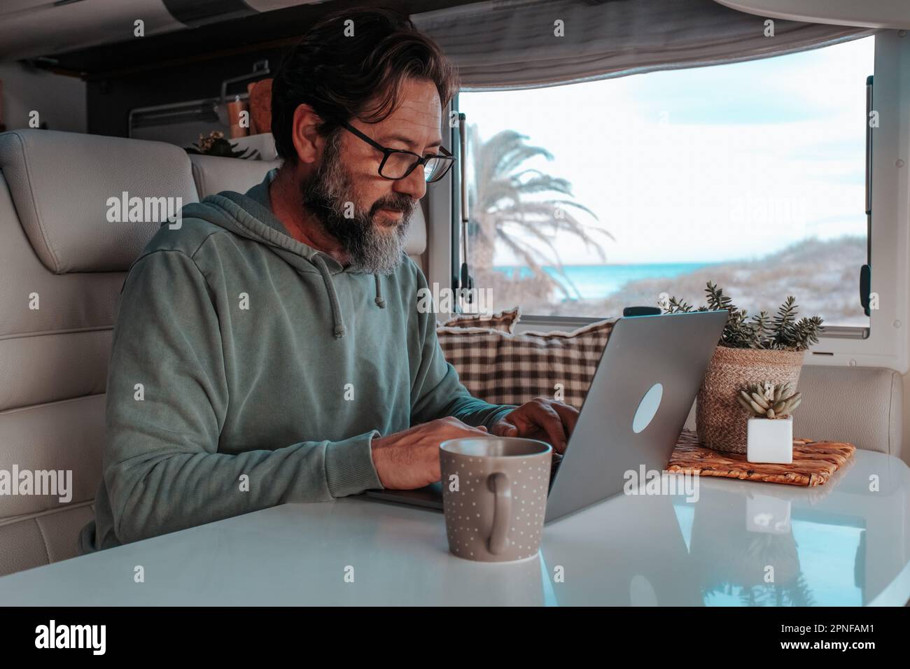 Uomo seduto a casa mobile e al lavoro sul notebook Foto Stock