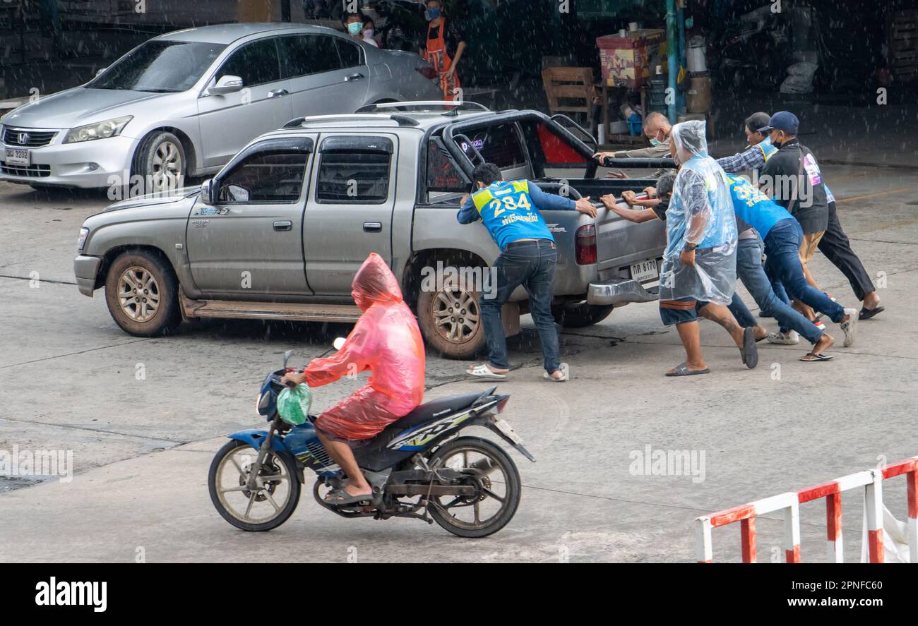 SAMUT PRAKAN, THAILANDIA, OTT 07 2022, gli uomini aiutano a spingere una macchina danneggiata sulla strada Foto Stock