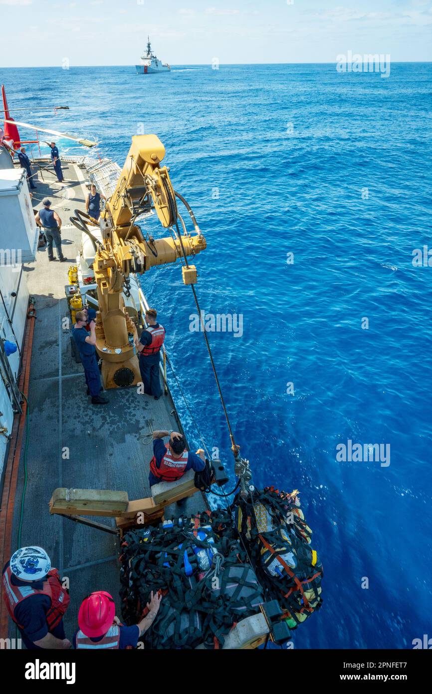 Equipaggio di coperta dagli Stati Uniti Coast Guard Cutter Active (WMEC 618) si prepara a trasferire balle di marijuana con una gru avita negli Stati Uniti Guardia costiera Cutter Waesche (WMSL 751) nell'Oceano Pacifico orientale, 25 marzo 2023. Attivo e l'equipaggio ha rilevato e sequestrato oltre 100 balle di marijuana in acque internazionali. (STATI UNITI Coast Guard foto di Petty Officer 2nd Classe Justin upshaw). Foto Stock