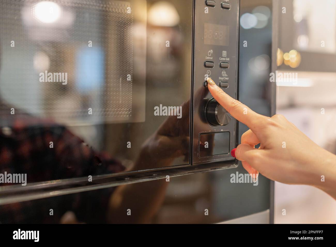 Primo piano femmina apertura o chiusura del moderno forno elettrico prepararsi a cucinare nella cucina moderna. Foto Stock