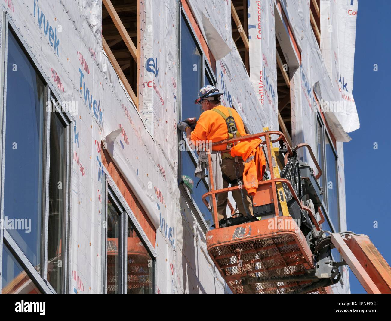 Operai edili che installano finestre in un alto edificio di appartamenti in costruzione. Foto Stock