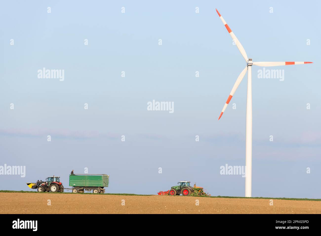 Trattore con rimorchio che semina grano in un campo, turbina eolica, centrale eolica, Albo Svevo, Baden-Wuerttemberg, Germania Foto Stock