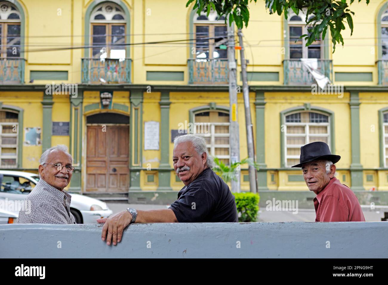 Uomini del Costa Rica su una panchina in Parque Central, l'ex scuola nella parte posteriore, Alajuela, Provincia di Alajuela, Costa Rica Foto Stock