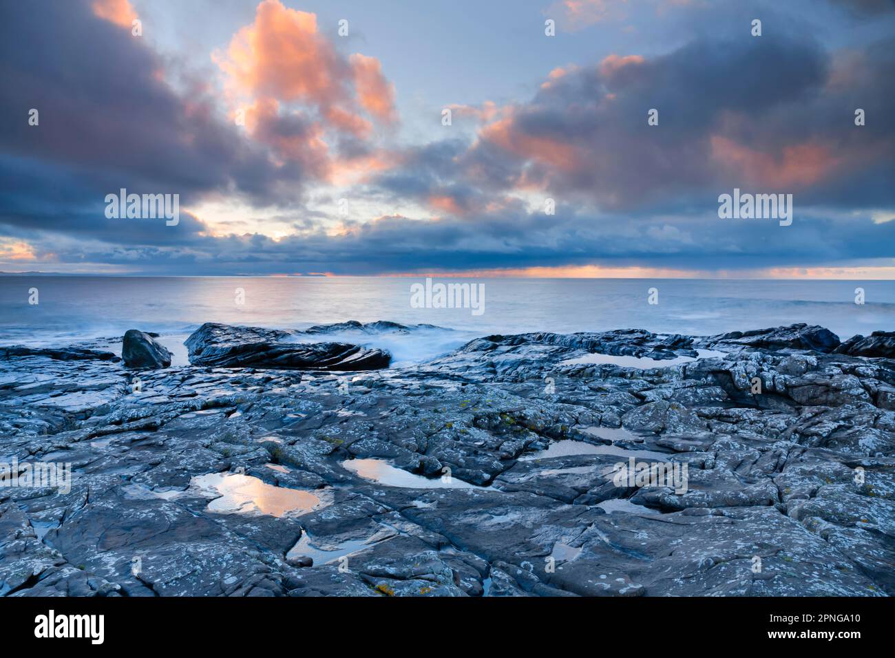 Basse nuvole di pioggia che si affacciano sulle acque aperte dell'Atlantico blu al tramonto con cielo nuvoloso di colore arancione, costa nord-occidentale della Scozia Foto Stock