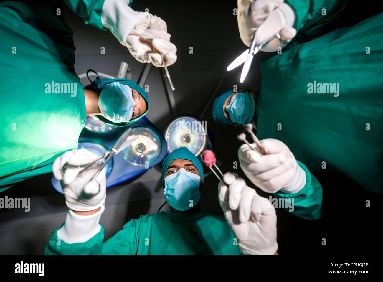 Gruppo di chirurghi e infermiere in abito verde chirurgico uniforme esecuzione intervento chirurgico in sala operatoria. Vista dal basso. Assistenza chirurgica di emergenza conce Foto Stock