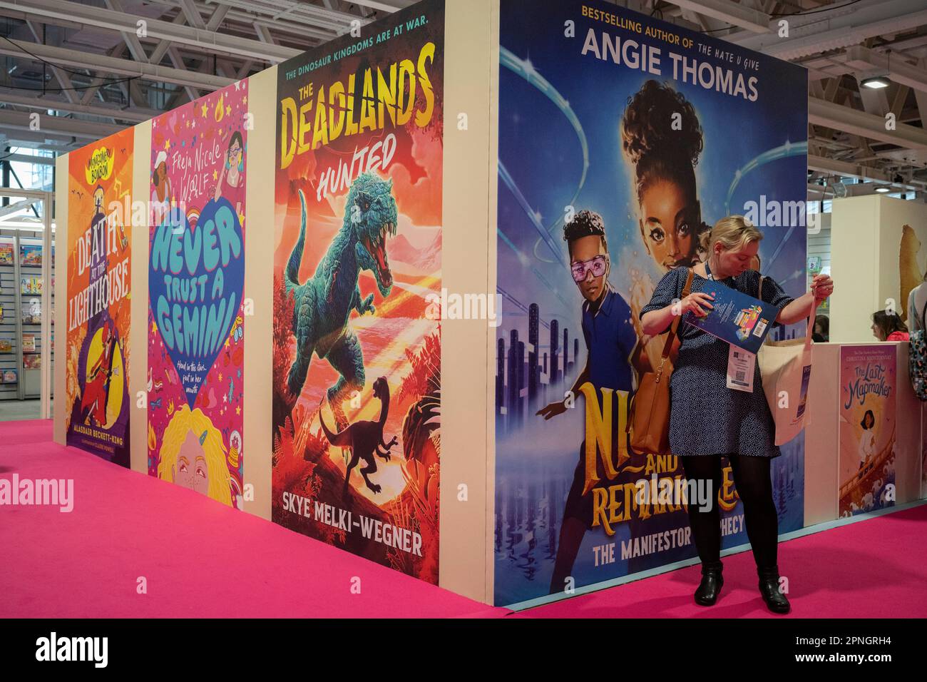 Un delegato e grandi annunci per i titoli di libri allo stand 'Walker Book Group' durante il primo giorno della Fiera del Libro di Londra presso l'Olympia Exhibition Hall di Hammersmith, il 18th aprile 2023, a Londra, Inghilterra. La fiera internazionale del libro di Londra (LBF), che si svolge tre giorni, è una fiera annuale del settore editoriale e la più grande fiera di primavera del libro d'Europa, che attira in genere 25.000 visitatori, espositori provenienti da tutto il settore editoriale, autori che sperano che le loro idee di libro vengano commissionate e dove vengono stipulati accordi internazionali sui diritti di pubblicazione per le edizioni straniere. Foto Stock