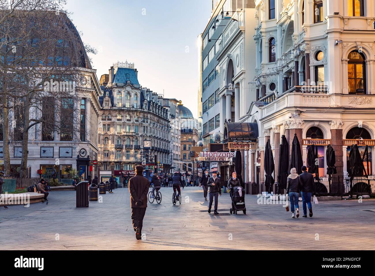 Persone che camminano a Leicester Square nel tardo pomeriggio durante la pandemia di Covid, Londra, Regno Unito Foto Stock