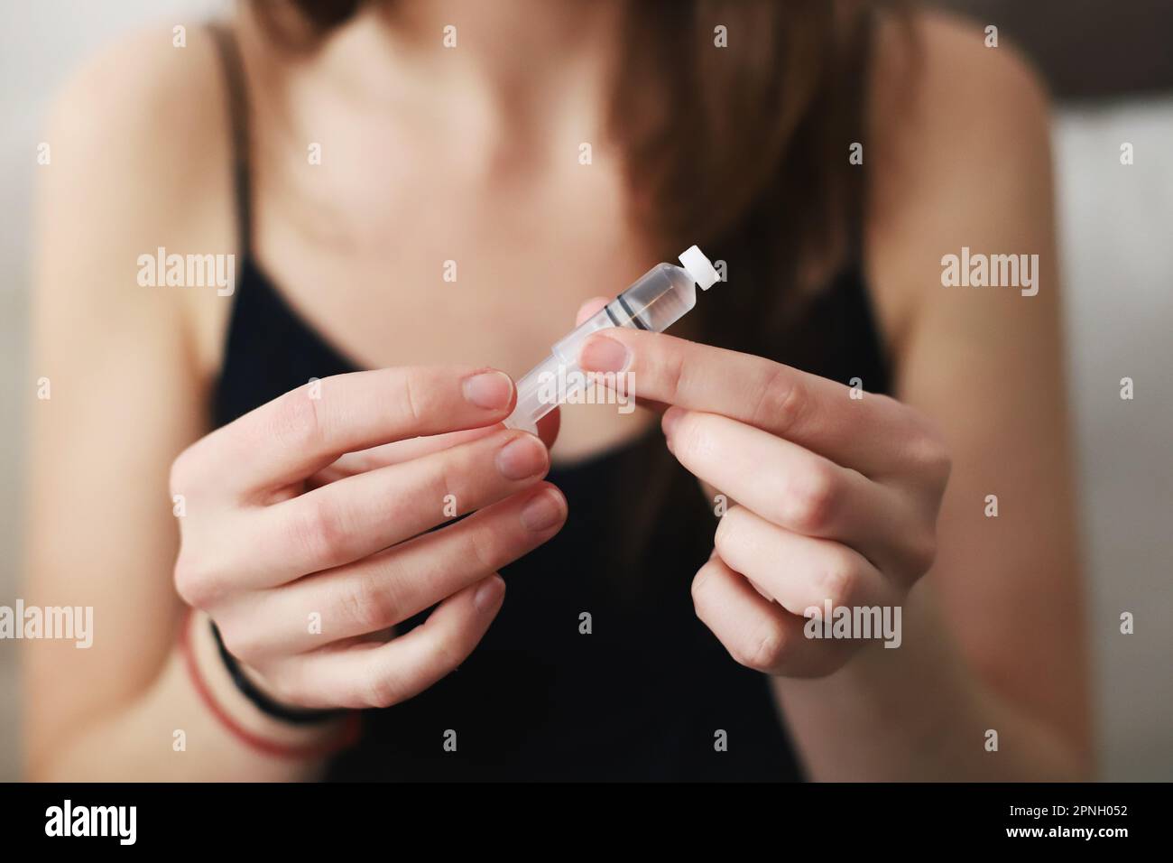 Donna che tiene un serbatoio appena riempito di insulina per la sua pompa di insulina Foto Stock