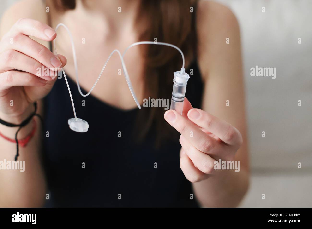 Donna che tiene un serbatoio appena riempito di insulina per la sua pompa di insulina Foto Stock