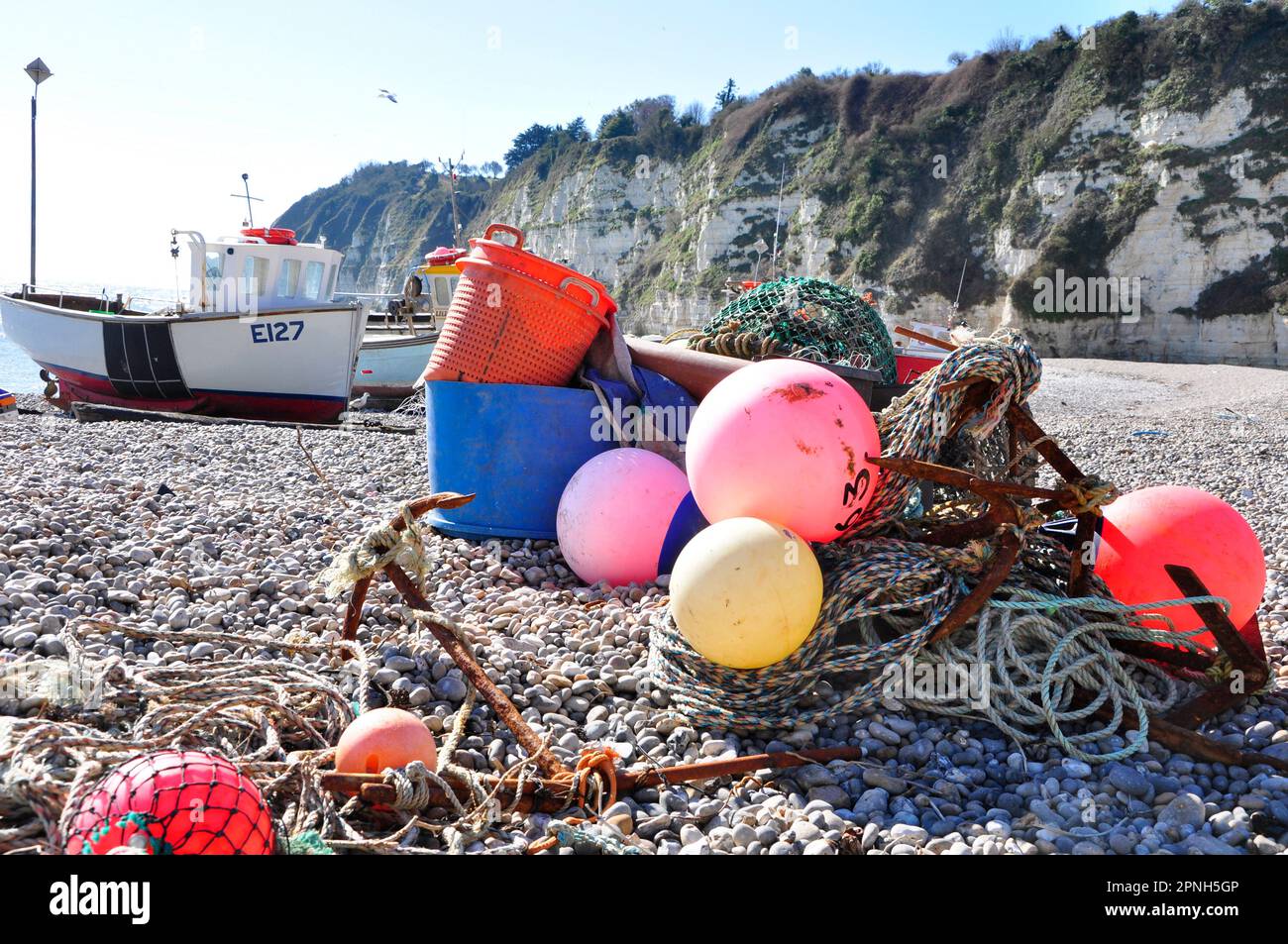 Barche e attrezzatura da pesca sulla spiaggia di ciottoli riparata dalle scogliere di gesso a Beer in Devon, Regno Unito. Foto Stock