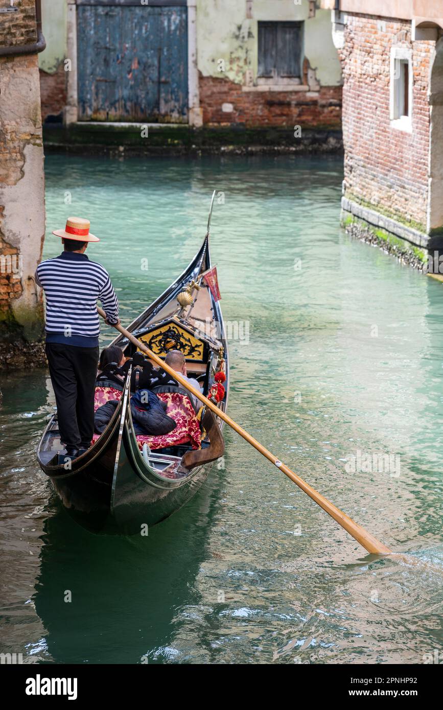 Gondoliere con cappello in gondola in un canale d'acqua, Venezia, Veneto, Italia Foto Stock