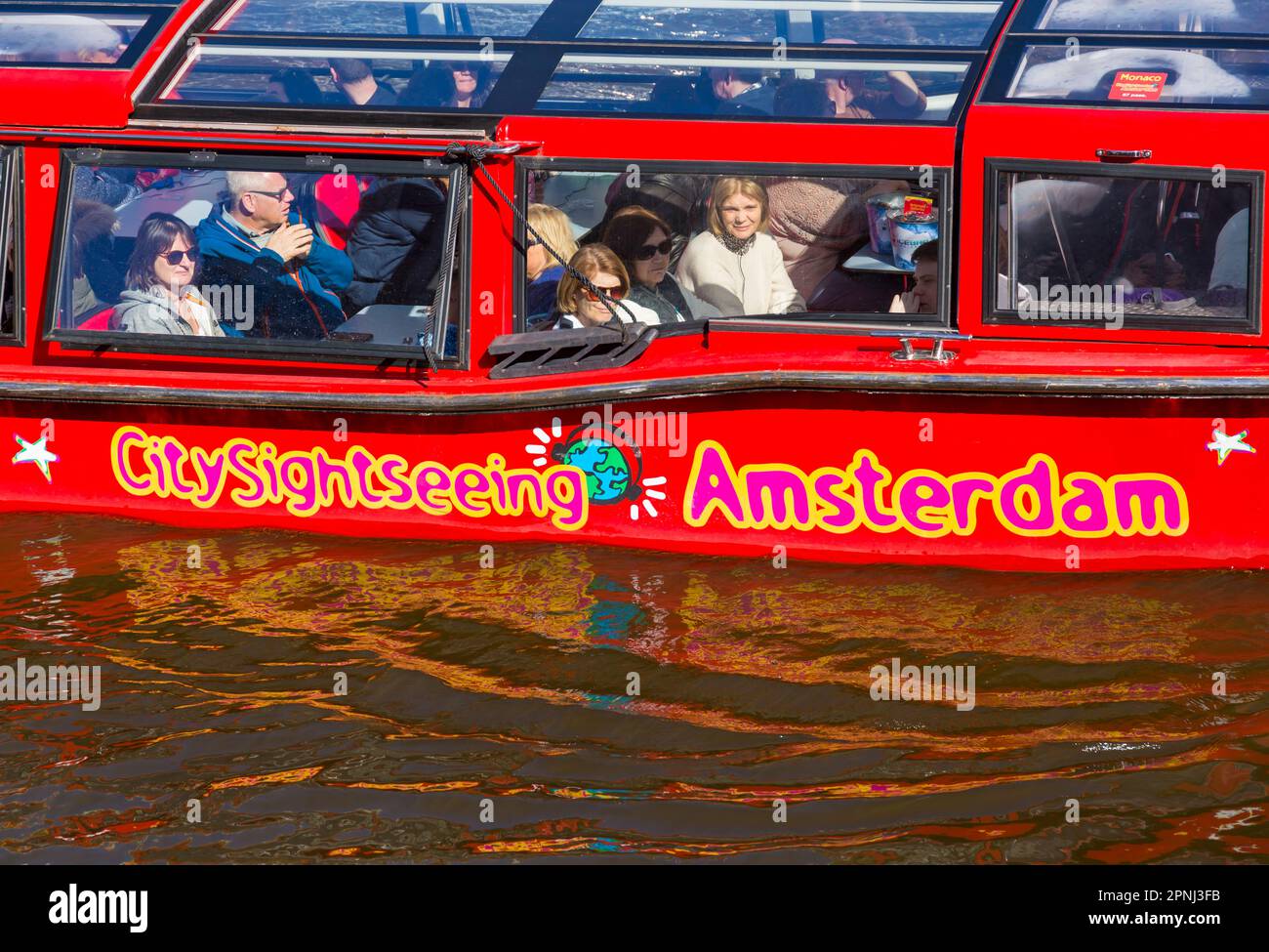 I turisti in giro turistico della città di Amsterdam in barca che viaggia lungo i canali ad Amsterdam, Olanda, Paesi Bassi nel mese di aprile Foto Stock