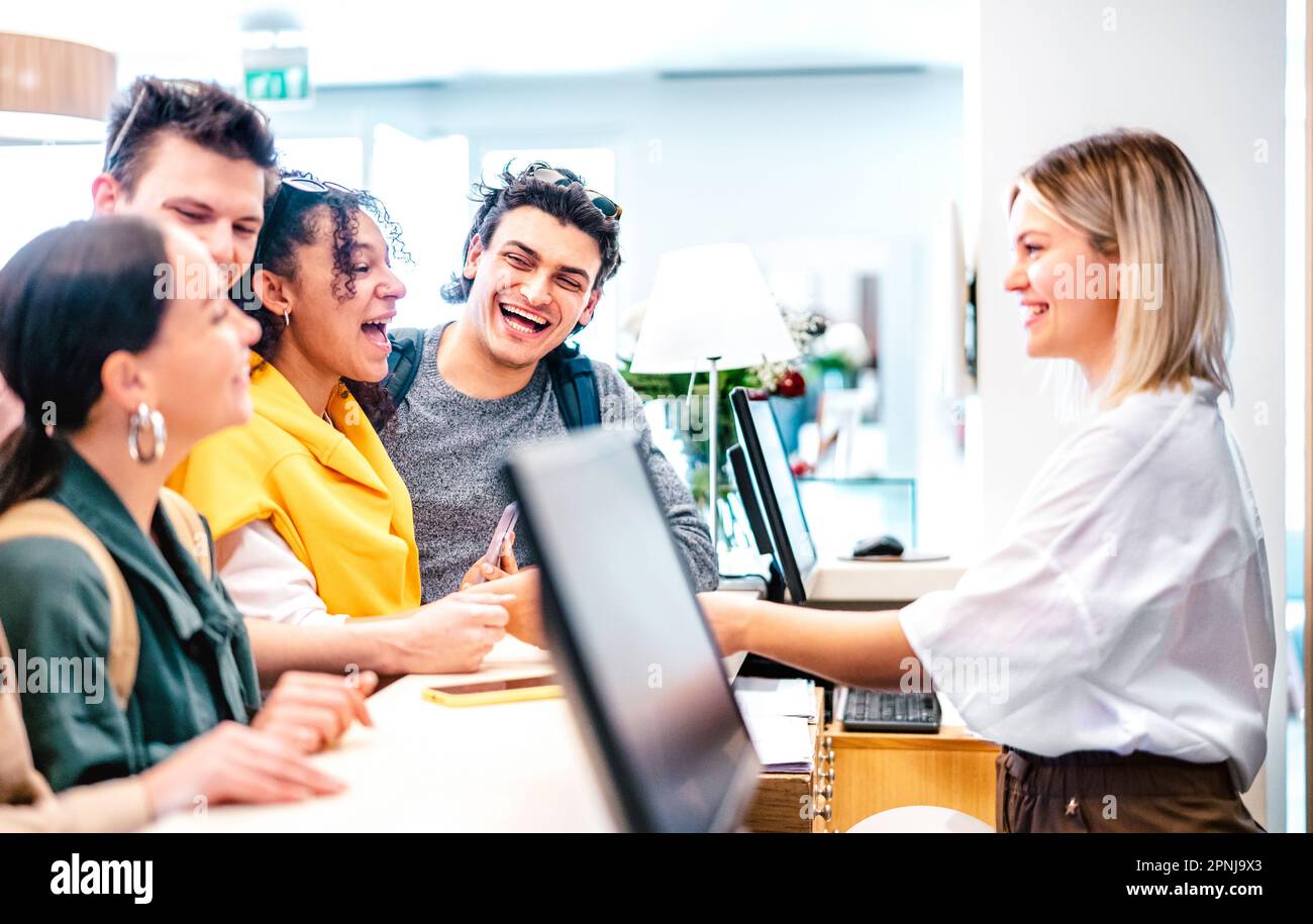 Giovani amici diversi divertirsi alla reception dell'hotel di lusso al momento del check-in - concetto di stile di vita di viaggio con persone felici in attesa alla pensione d Foto Stock