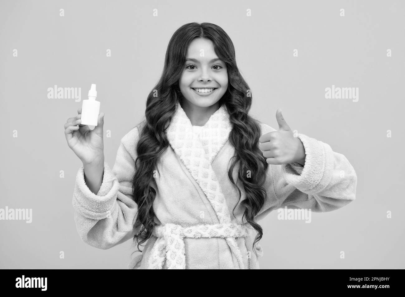 Naso tondo e allergia, spray nasale. Ragazza teen in pajama uso gocce nasali, naso imbottito isolato su sfondo giallo. Foto Stock