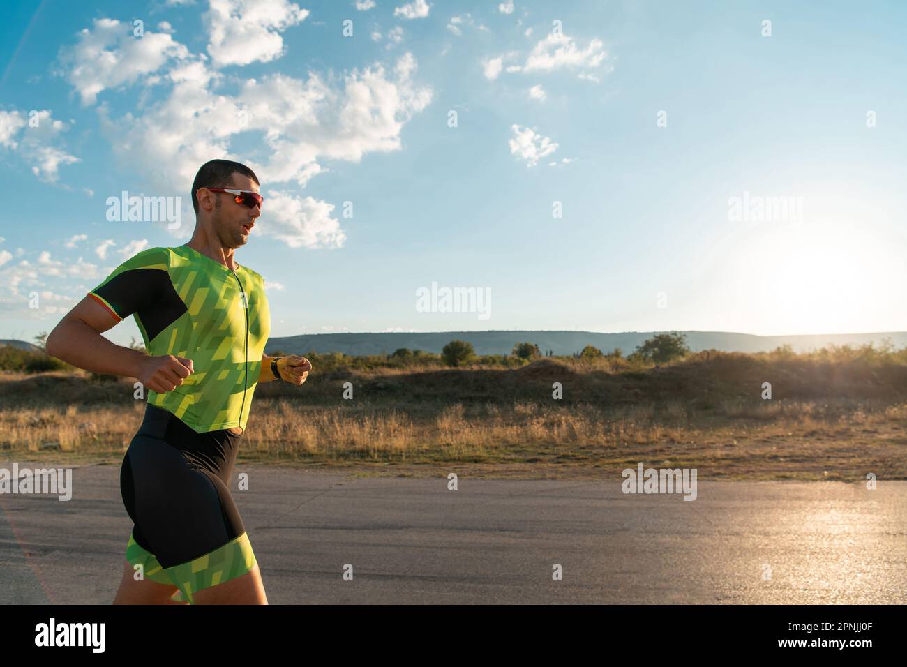 Il triatleta in attrezzatura professionale corre la mattina presto, preparandosi per una maratona, la dedizione allo sport e la disponibilità ad affrontare le sfide di Foto Stock