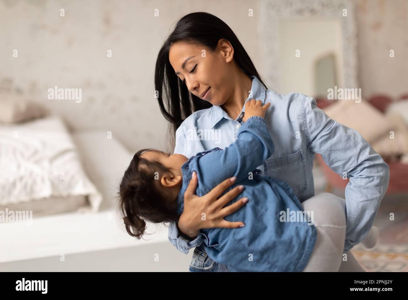 Madre asiatica Lulling piccola figlia bambino a dormire a casa Foto Stock