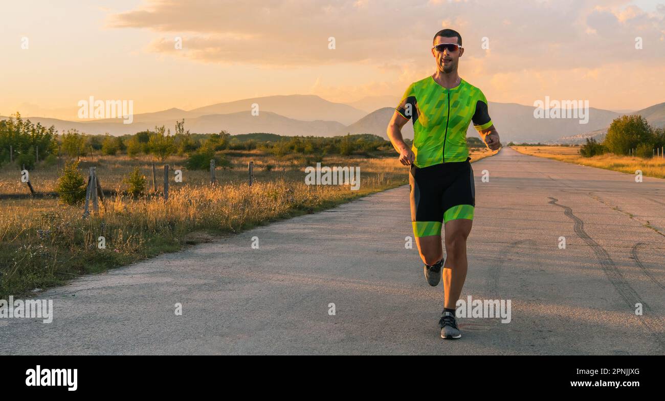 Il triatleta in attrezzatura professionale corre la mattina presto, preparandosi per una maratona, la dedizione allo sport e la disponibilità ad affrontare le sfide di Foto Stock