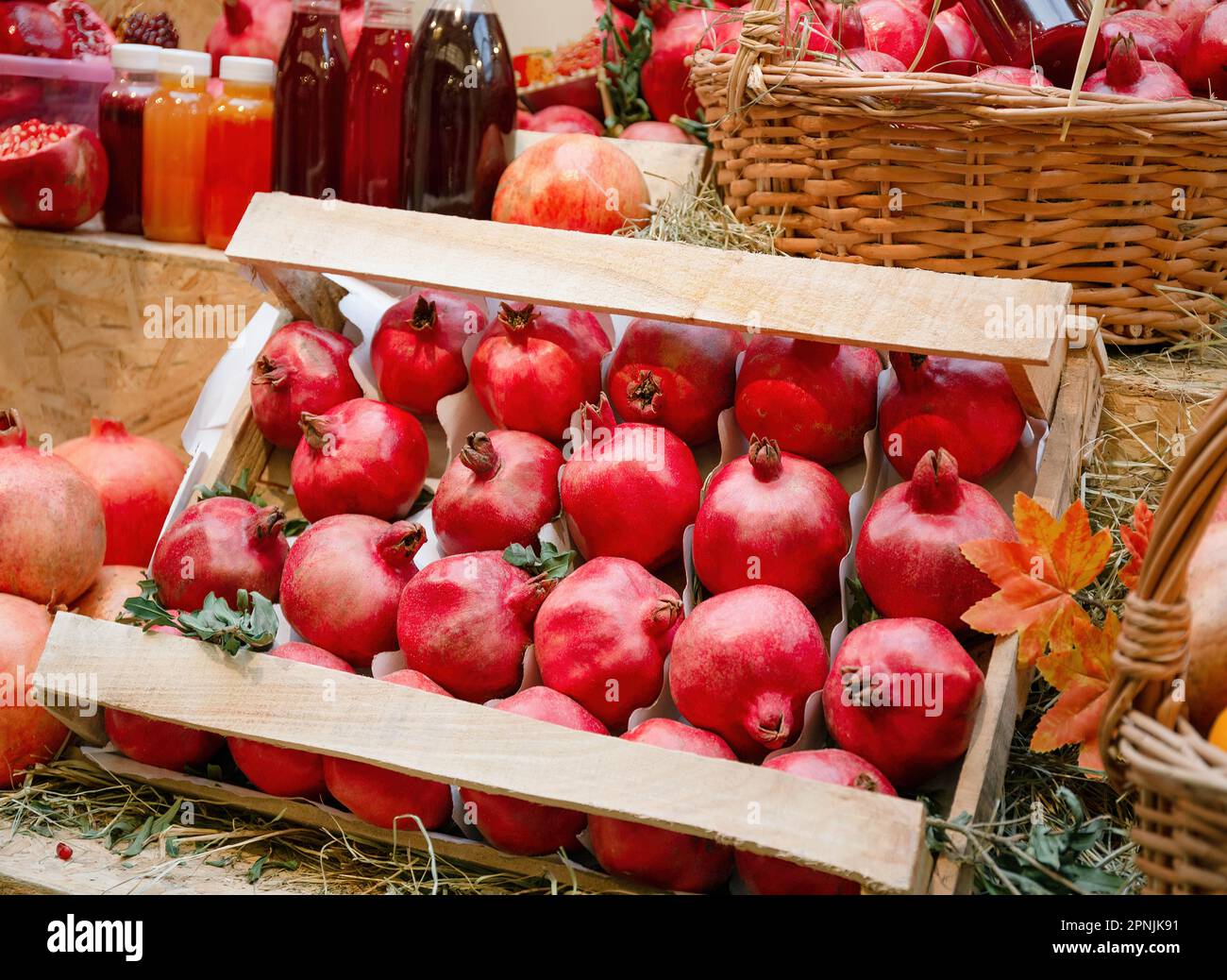 Melograno rosso maturo sul banco nel mercato o nel supermercato, un cesto pieno di tangerini, frutta biologica, dieta vitaminica Foto Stock