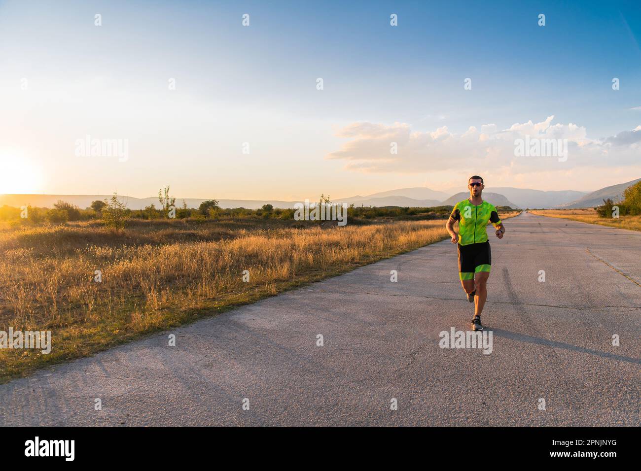 Il triatleta in attrezzatura professionale corre la mattina presto, preparandosi per una maratona, la dedizione allo sport e la disponibilità ad affrontare le sfide di Foto Stock