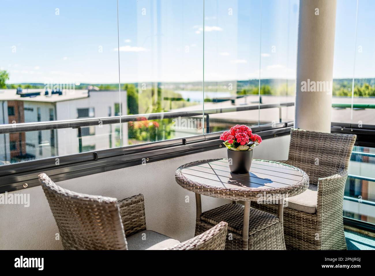 Balcone in estate. Patio privato con vista. Appartamento in condominio in città. Decorazioni e arredi scandinavi. Finestre in vetro, vetri. Fiore o pianta. Foto Stock