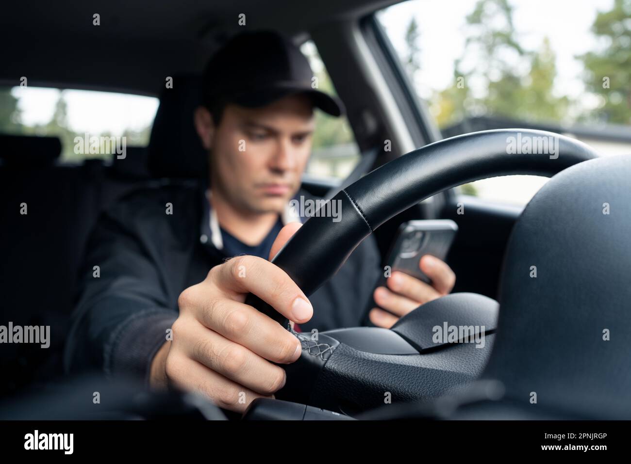 Guidare l'auto e utilizzare il telefono per inviare messaggi di testo. Conducente che utilizza il cellulare. Incidenti, incidenti e pericolo di traffico. Man che ti fa inviare messaggi con l'app mobile. Foto Stock