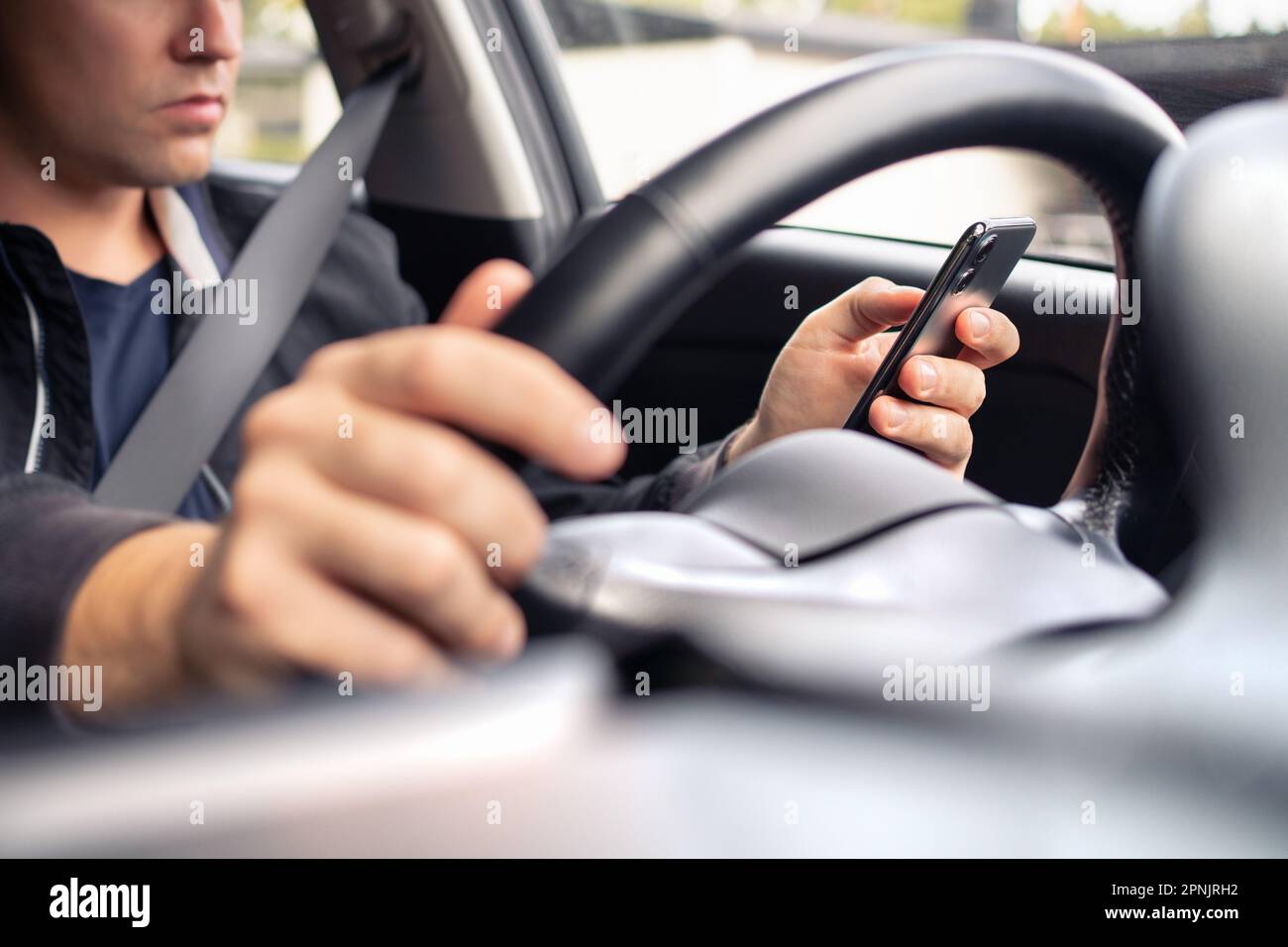 Inviare SMS e guidare un'auto. Utilizzo del telefono cellulare nel traffico. Conducente distratto, incidente o incidente. Uomo irresponsabile che digita un SMS. Foto Stock