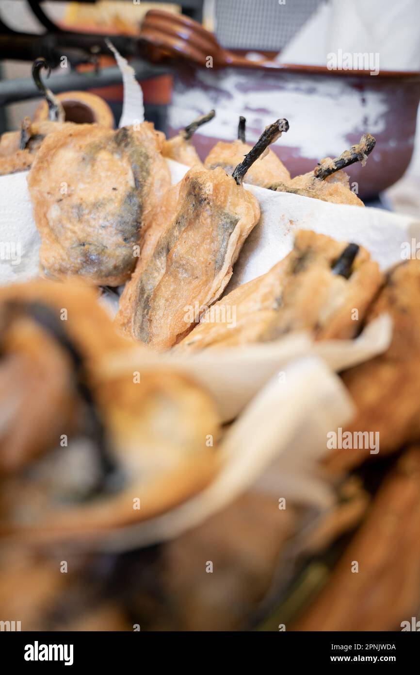 Primo piano di alcuni peperoncini poblano appena cotti in pastella all'interno di una grande casseruola di argilla tradizionale Foto Stock