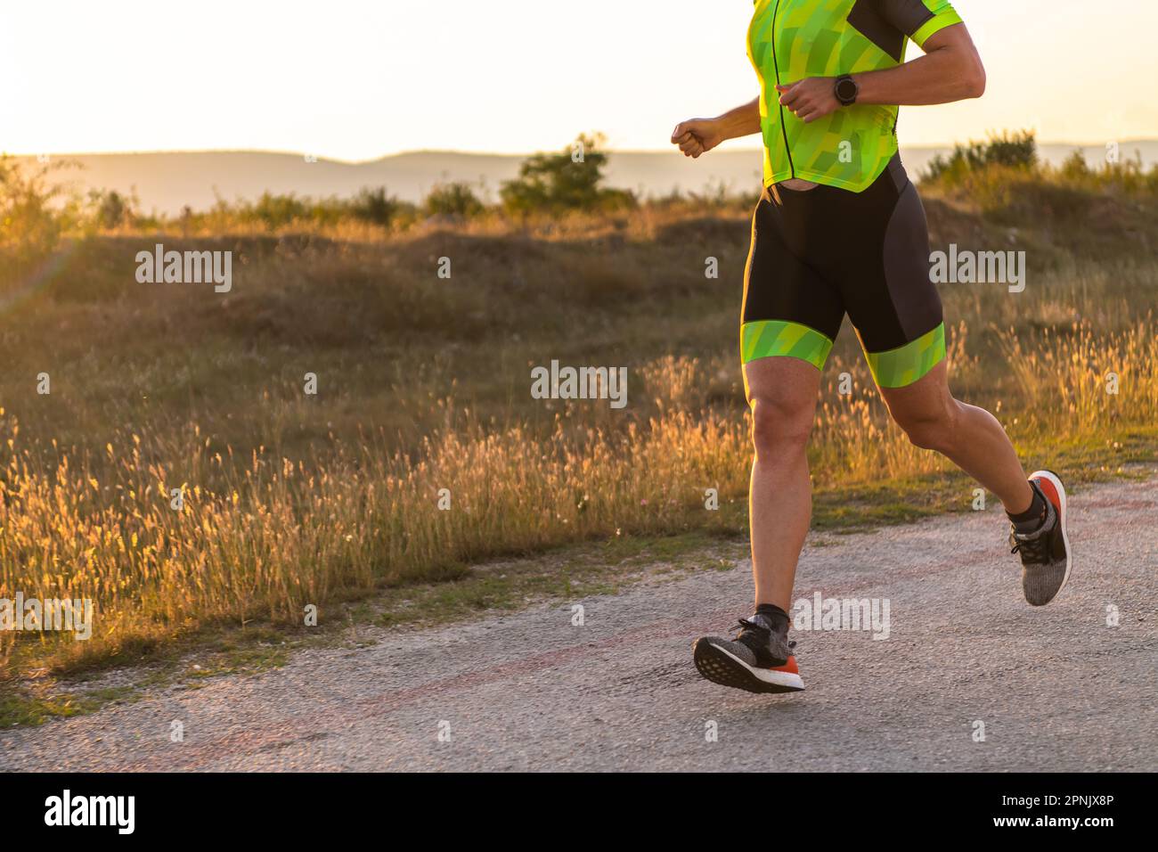 Il triatleta in attrezzatura professionale corre la mattina presto, preparandosi per una maratona, la dedizione allo sport e la disponibilità ad affrontare le sfide di Foto Stock