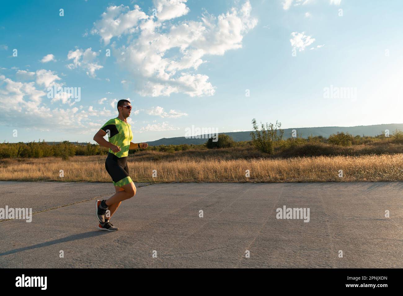 Il triatleta in attrezzatura professionale corre la mattina presto, preparandosi per una maratona, la dedizione allo sport e la disponibilità ad affrontare le sfide di Foto Stock