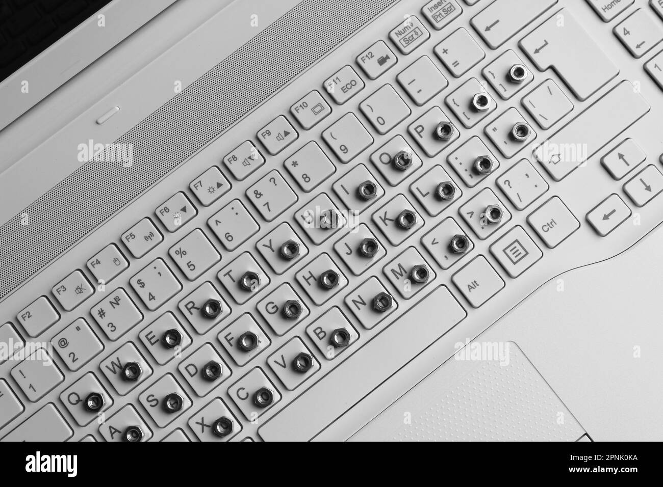 I dadi metallici si sovrappongono ai simboli sulla tastiera bianca di un computer Foto Stock