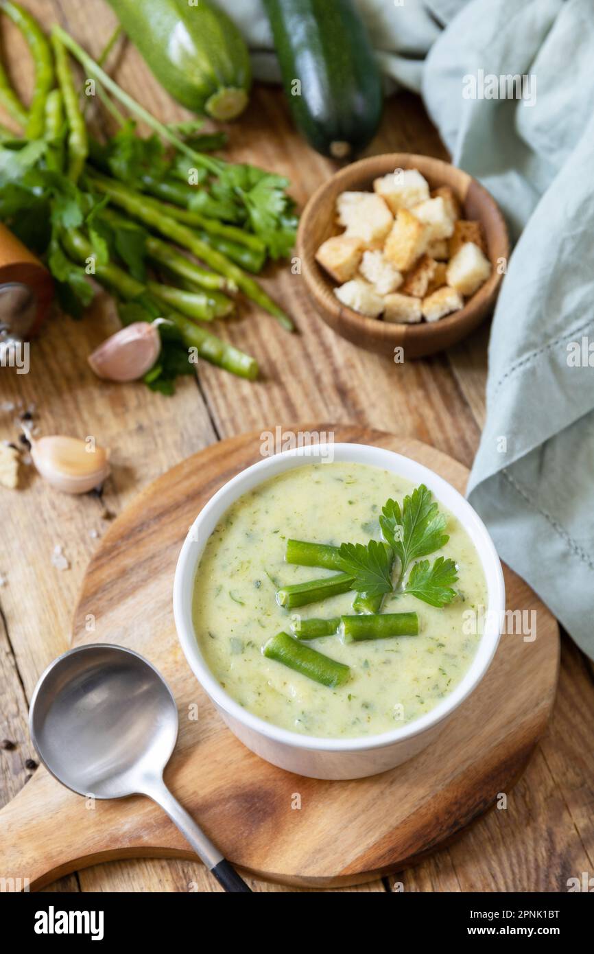 Purea di verdure verdi per zuppa vegana. Ciotola di fagiolo verde e zuccini crema su un tavolo rustico. Dieta sana basso carb. Foto Stock