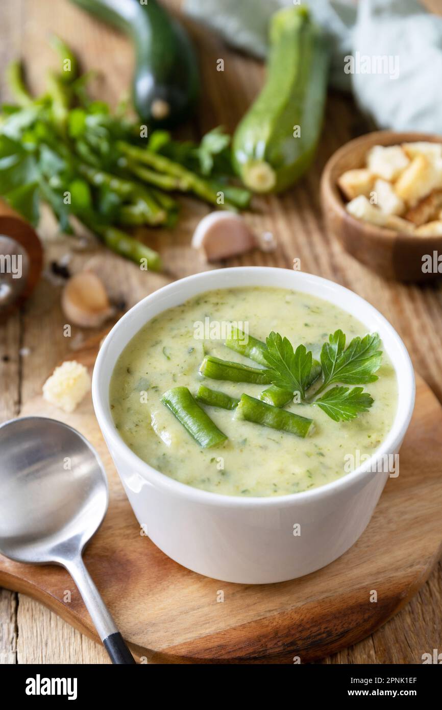 Purea di verdure verdi per zuppa vegana. Dieta sana basso carb. Ciotola di fagiolo verde e zuccini crema su un tavolo rustico. Foto Stock