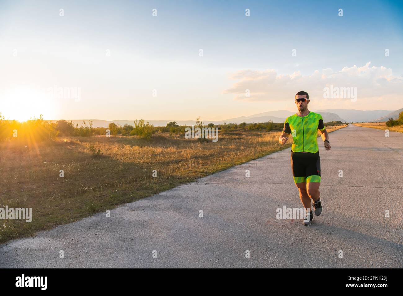 Il triatleta in attrezzatura professionale corre la mattina presto, preparandosi per una maratona, la dedizione allo sport e la disponibilità ad affrontare le sfide di Foto Stock