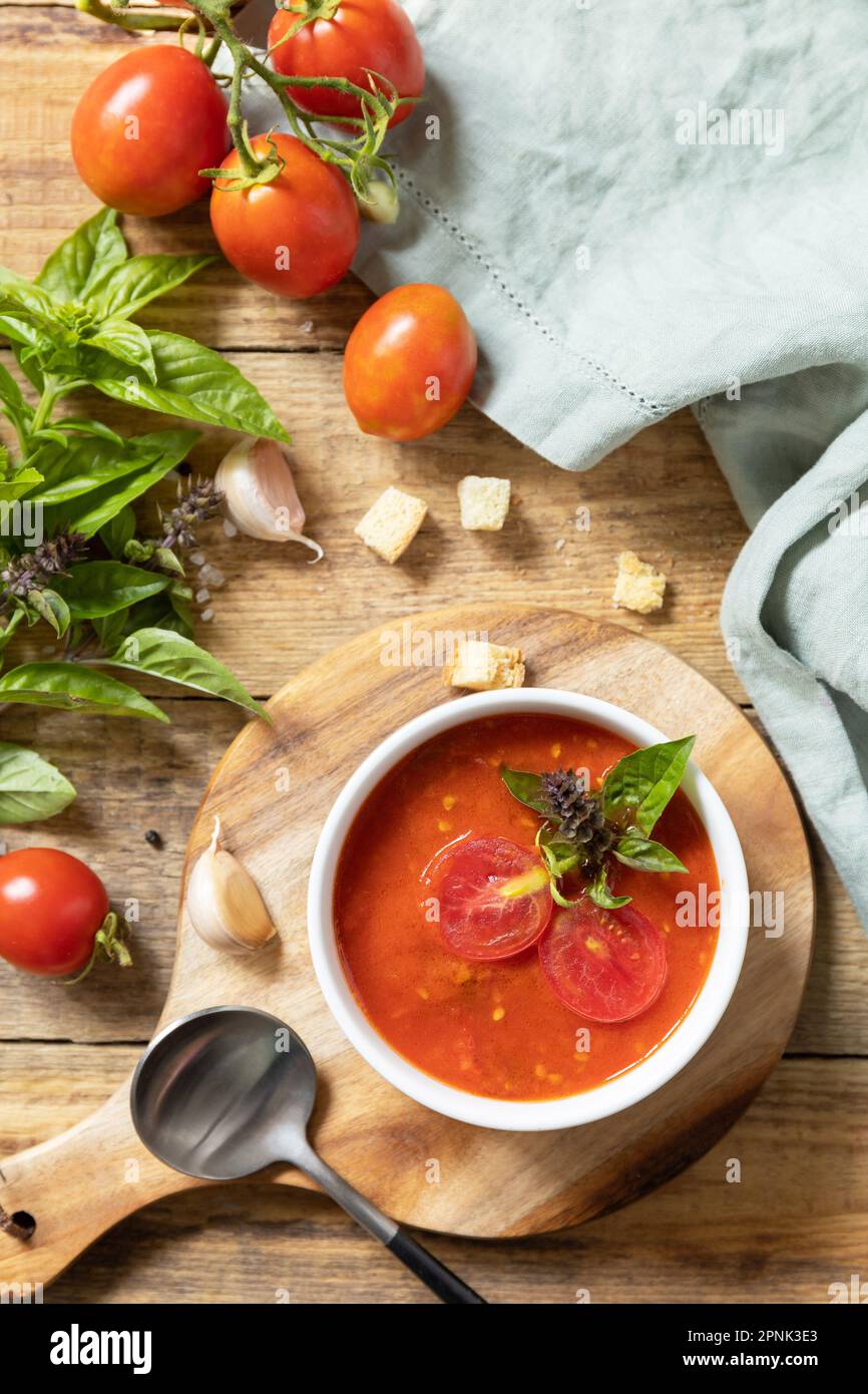 Ciotola di zuppa di crema di pomodoro con basilico e crostini su un tavolo rustico. Zuppa vegana pomodori purè. Dieta sana basso carb. Vista dall'alto. Foto Stock