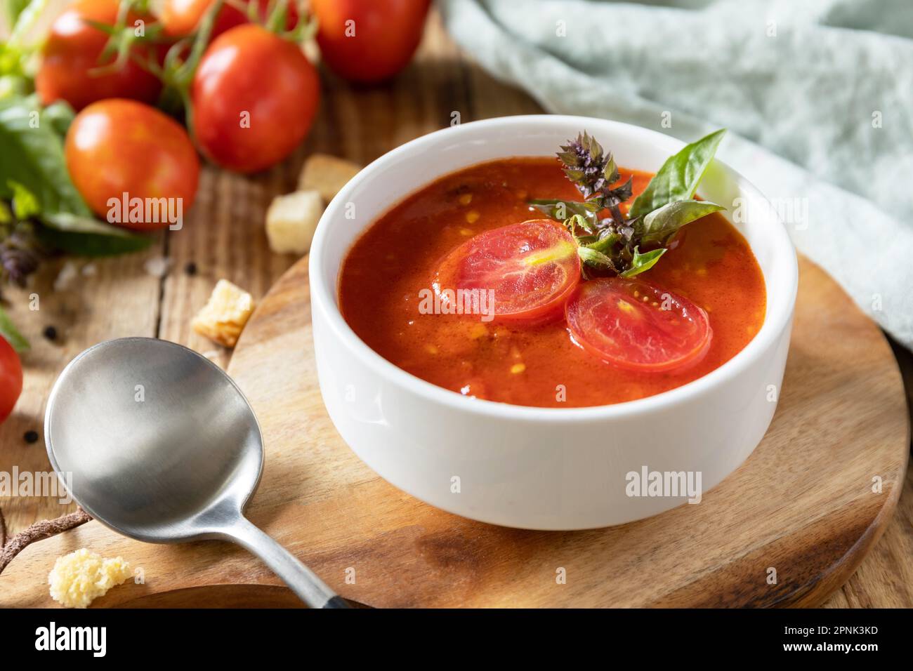 Ciotola di zuppa di crema di pomodoro con basilico e crostini su un tavolo rustico. Zuppa vegana pomodori purè. Dieta sana basso carb. Foto Stock