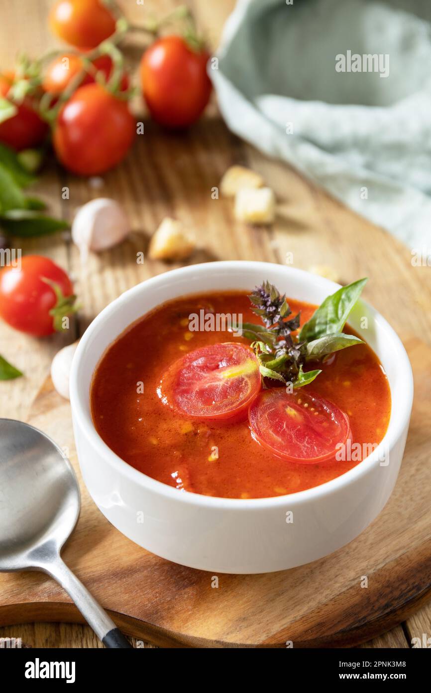 Zuppa vegana pomodori purè. Dieta sana basso carb. Ciotola di zuppa di crema di pomodoro con basilico e crostini su un tavolo rustico. Foto Stock