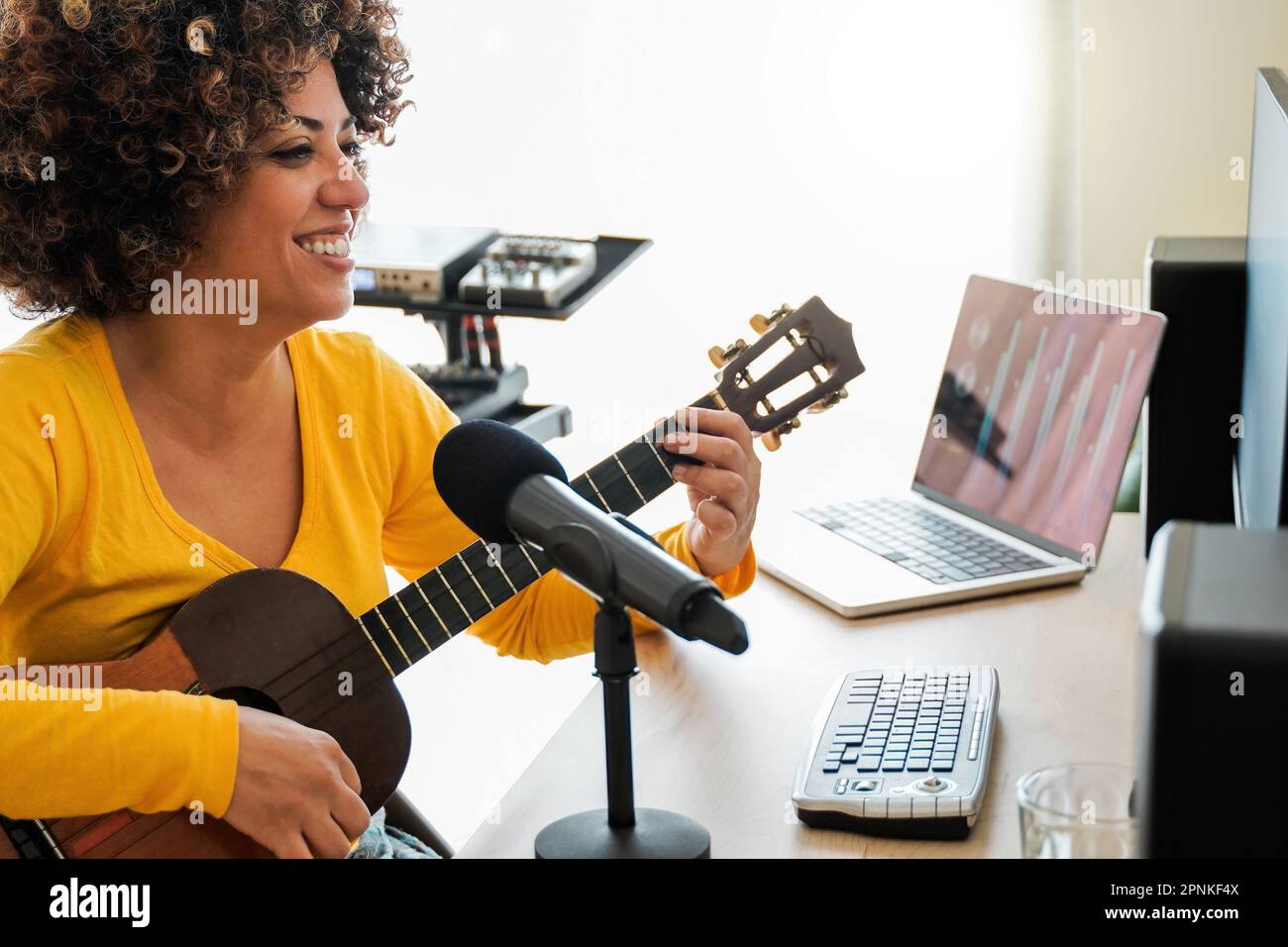Musicista africano insdie musica home studio registrazione ukulele chitarra canzone - Audio ingegnere donna mixing album - Soft focus su donna viso Foto Stock
