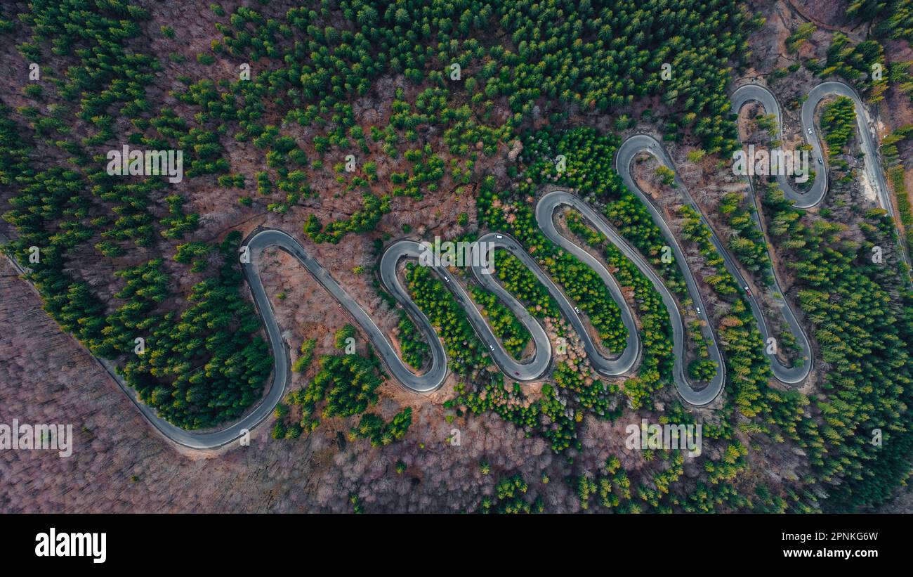 Fotografia aerea di una strada tortuosa in montagna con serpentine e curve. La fotografia è stata scattata da un drone ad un'altitudine più alta. Foto Stock