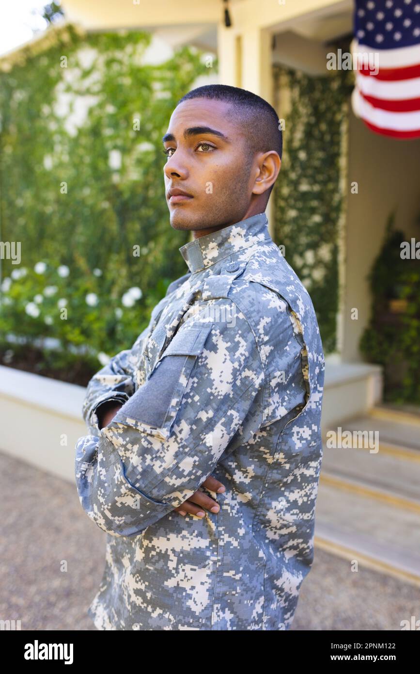 Soldato americano maschio biraciale che indossa uniforme militare in piedi fuori casa e guardando lontano Foto Stock
