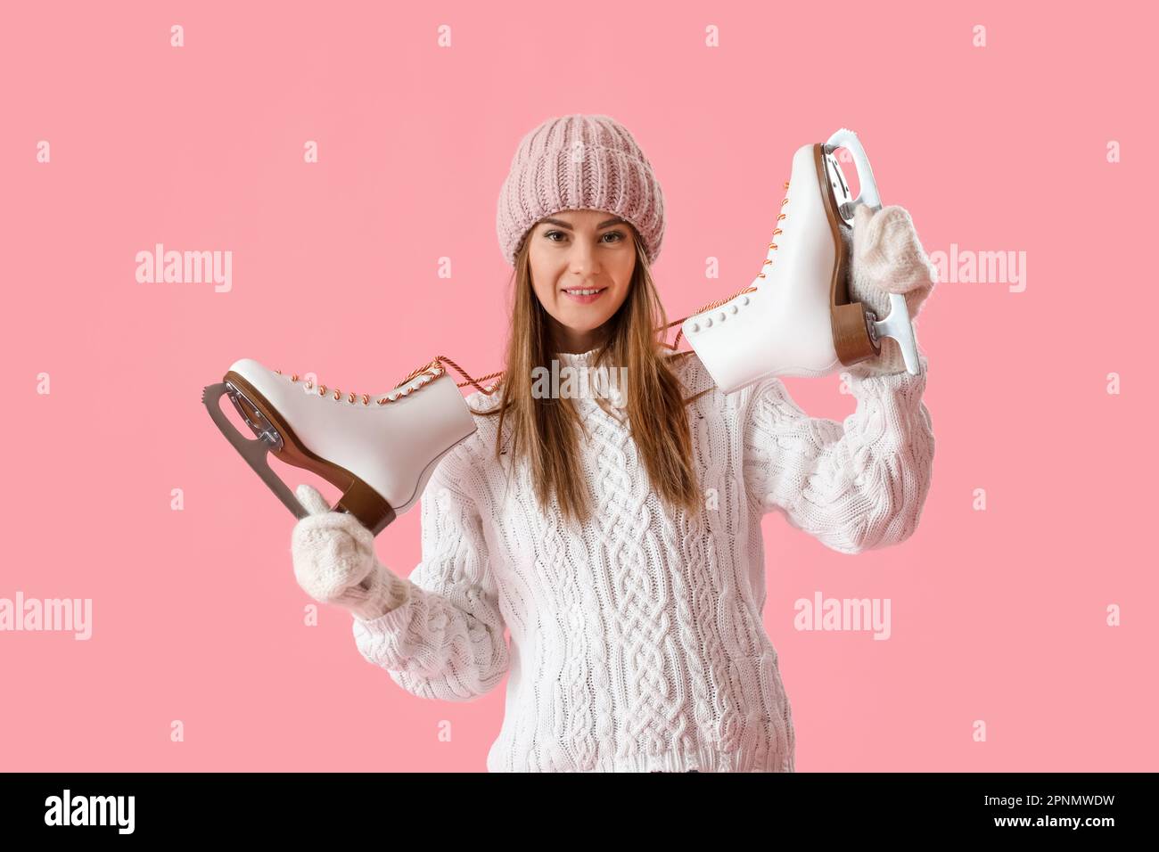 Bella giovane donna con pattini di ghiaccio su sfondo rosa Foto Stock