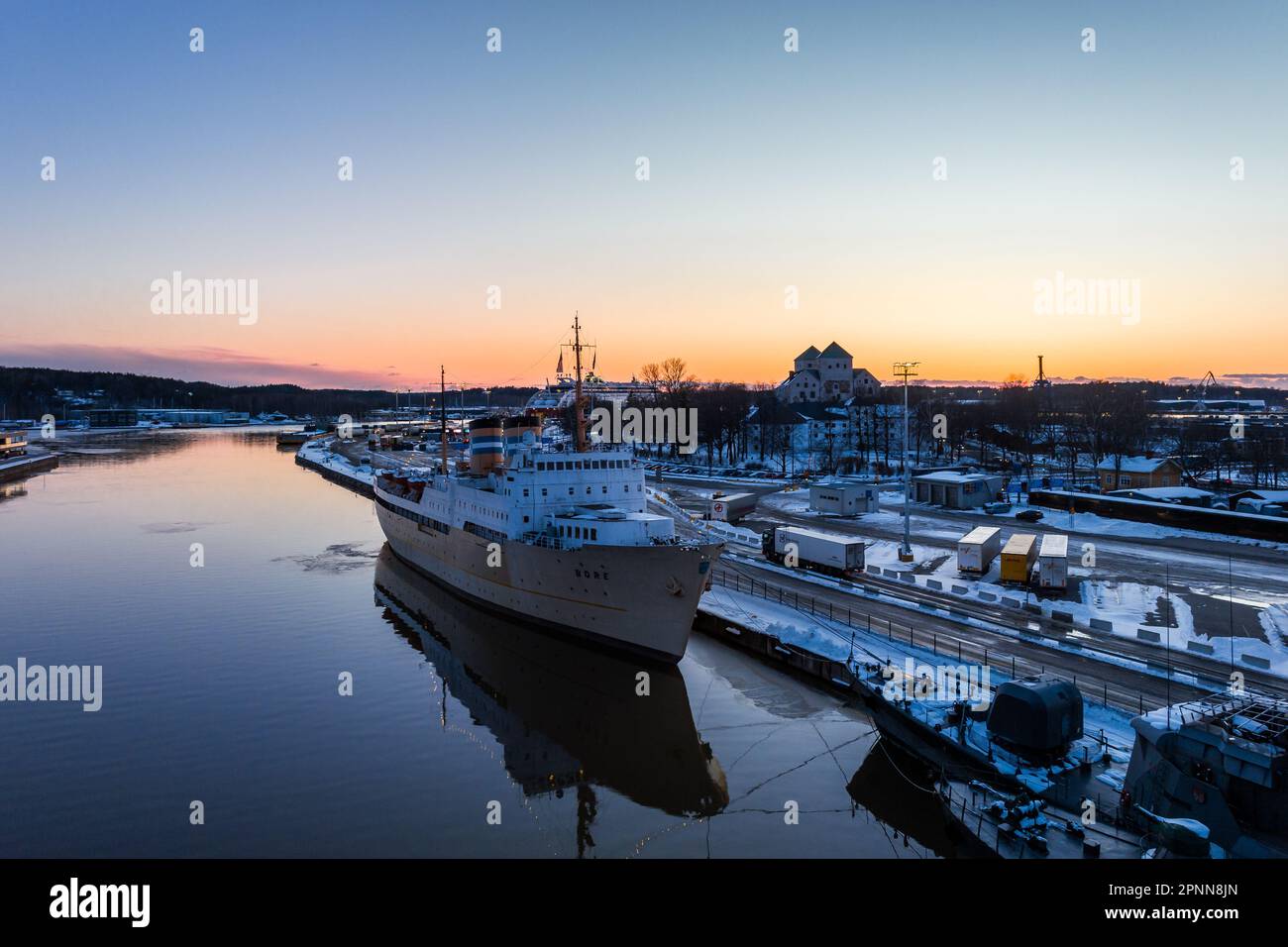 Turku, Finlandia - Marzo 2023: La nave d'albergo partorì nella sera d'inverno e il Castello di Turku sullo sfondo Foto Stock