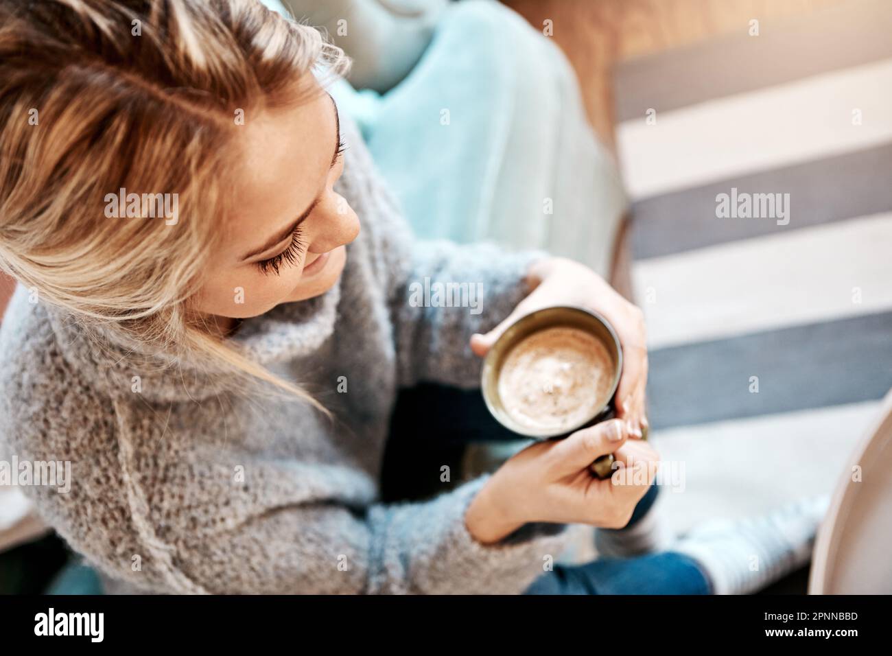 Oggi è lento. una giovane donna che si rilassa sul divano di casa con una bevanda calda. Foto Stock
