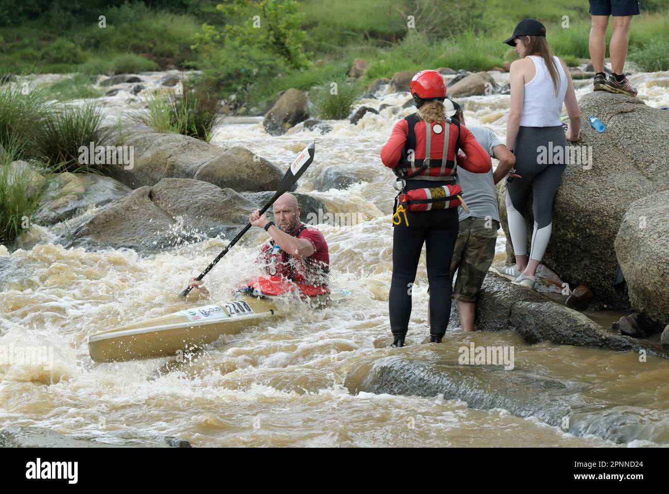 Spettatori che guardano un concorrente maschile adulto, Dusi Canoe Marathon 2023, evento sportivo, Durban, Sudafrica, competizione sportiva estrema, montare un uomo a pagaiare Foto Stock