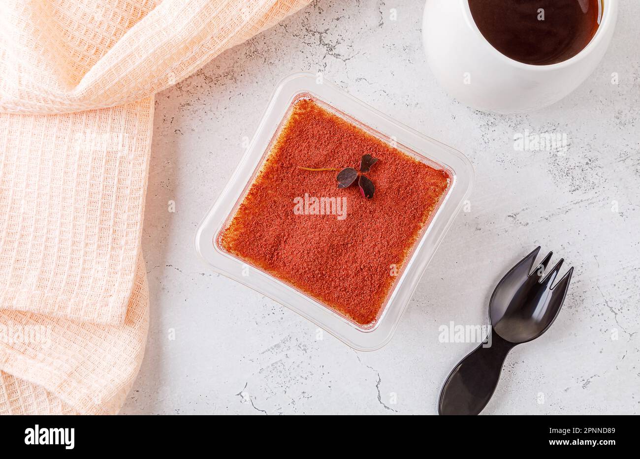 Dessert tiramisù in una scatola di plastica con forchetta su fondo di cemento. Foto di alta qualità Foto Stock