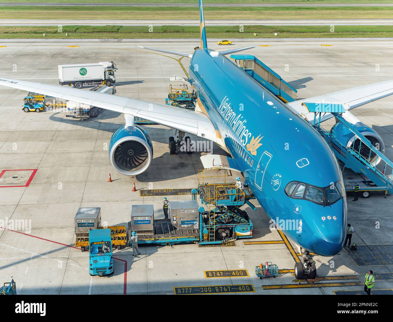 Vietnam Airlines Airbus A350 all'aeroporto internazionale noi Bai (NIA), il principale aeroporto di Hanoi, la capitale del Vietnam. Caricamento dei contenitori di carico Foto Stock